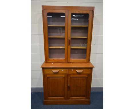 AN EARLY 20TH CENTURY OAK GLAZED TWO DOOR BOOKCASE, two drawers above two fielded panel doors, width 108cm x depth 48cm x hei