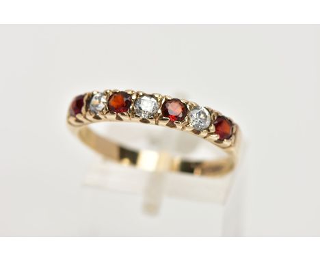 A 9CT GOLD GARNET AND CUBIC ZIRCONIA HALF ETERNITY RING, designed with a row of four circular cut garnets interspaced with co