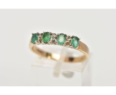 A 9CT GOLD EMERALD AND DIAMOND HALF ETERNITY RING, designed with a row of four claw set oval cut emeralds, interspaced with s