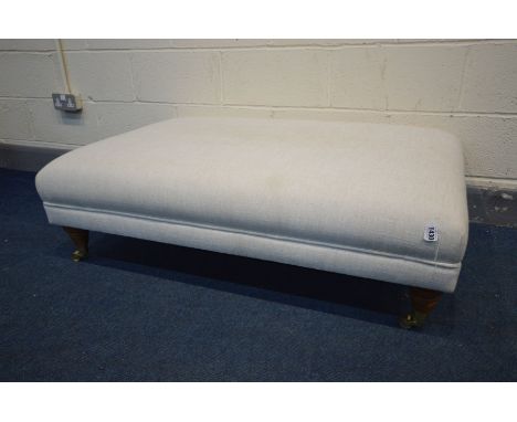 A LARGE MODERN POUFFE  in cream, turned legs on brass casters, width 117cm x depth 77cm x height 37cm