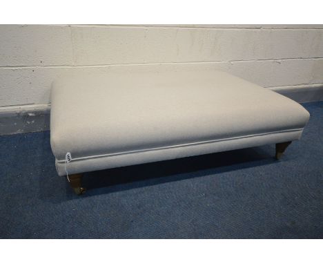 A LARGE MODERN POUFFE in herringbone fabric in grey, turned legs on brass casters, width 117cm x depth 77cm x height 37cm