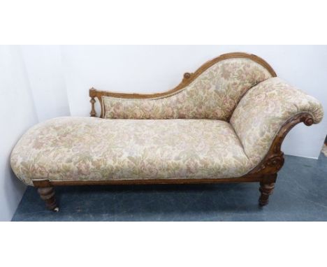 Late Victorian walnut scroll-back chaise longue, upholstered in later floral fabric, carved with applied roundels and acanthu