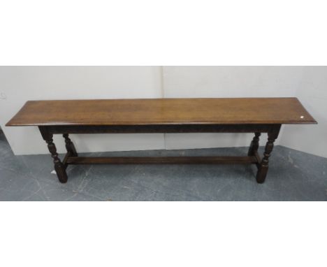 Victorian-style oak bench with plank top, incised decoration to the frieze, on turned columns and block supports with adjoini