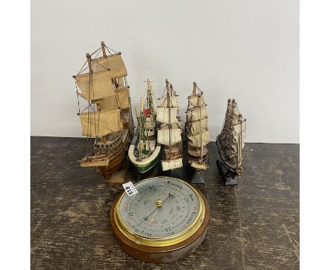 A wall mounted barometer and five model ships.