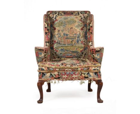 AN EARLY GEORGE II WALNUT AND NEEDLEWORK UPHOLSTERED WING ARMCHAIR CIRCA 1730 The needlework to the back depicting a fashiona