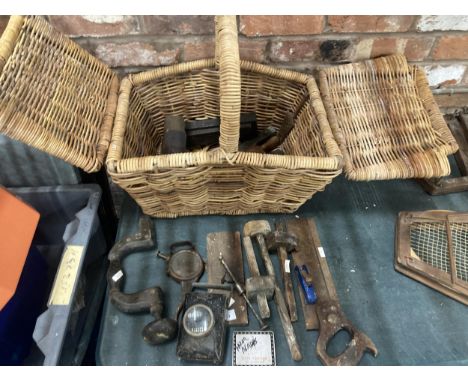 A WICKER BASKET CONTAINING A QUANTITY OF VINTAGE TOOLS TO INCLUDE WOODEN MALLETS, PLANES, A LAMP, ETC 