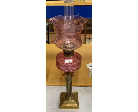A VINTAGE BRASS CORNINTHIAN COLUMN OIL LAMP WITH CRANBERRY GLASS RESERVOIR, HEIGHT 72CM 