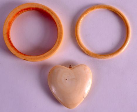 AN EARLY 20TH CENTURY EUROPEAN CARVED IVORY BANGLE together with another & a heart shaped pendant. (3)