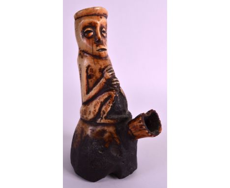 AN EARLY 20TH CENTURY CARVED AFRICAN BONE PIPE of figural form, modelled with hands clasped. 8.25ins high.