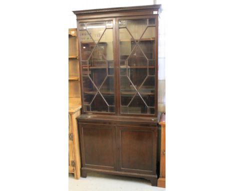 Mid 20th Century mahogany cupboard bookcase in Georgian style, dentil cornice over two astragal glazed doors, projecting base