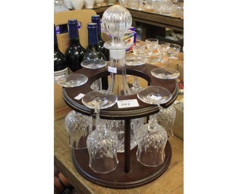 Set of six wine glasses with mallet shaped decanter and stopper on stained hardwood, modern stand.