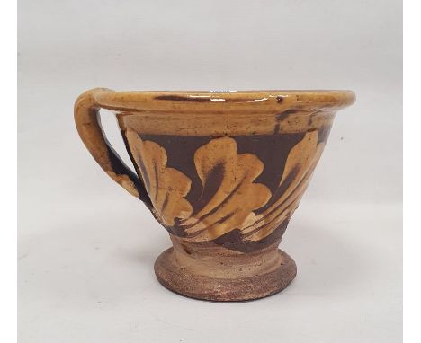 19th century Staffordshire pottery slipware conical bowl, decorated in cream slip with band of foliage, with loop handle, on 