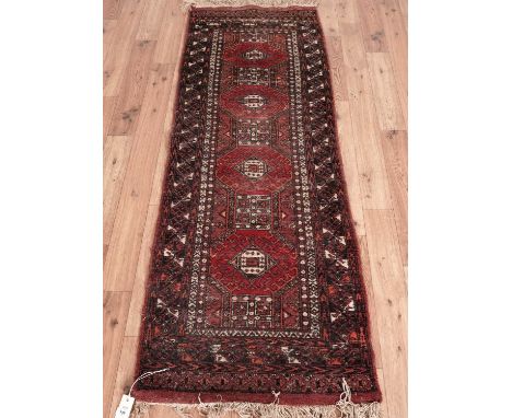 A Bokhara small runner, with central red hooked medallions and lozenge border, 64 x 182cms.