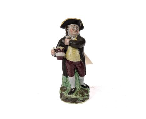A 19th Century decorative ceramic toby jug, modelled as a man standing on a grass base, the handle in the form of tree trunk,