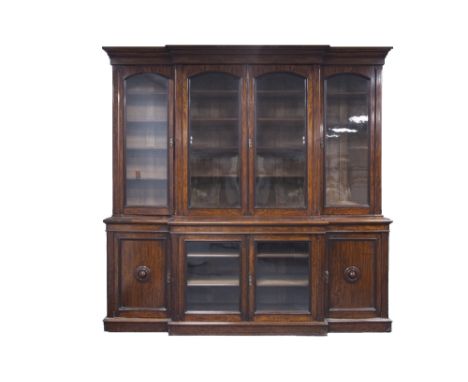 VICTORIAN AND LATER GRAIN PAINTED TO MAHOGANY BREAKFRONT LIBRARY BOOKCASE, the moulded cornice above four cupboard doors with