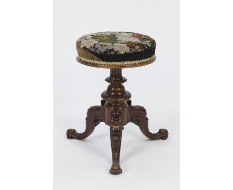 VICTORIAN CARVED WALNUT ADJUSTABLE PIANO STOOL, the padded circular seat with hand worked floral needlework cover, above a ca