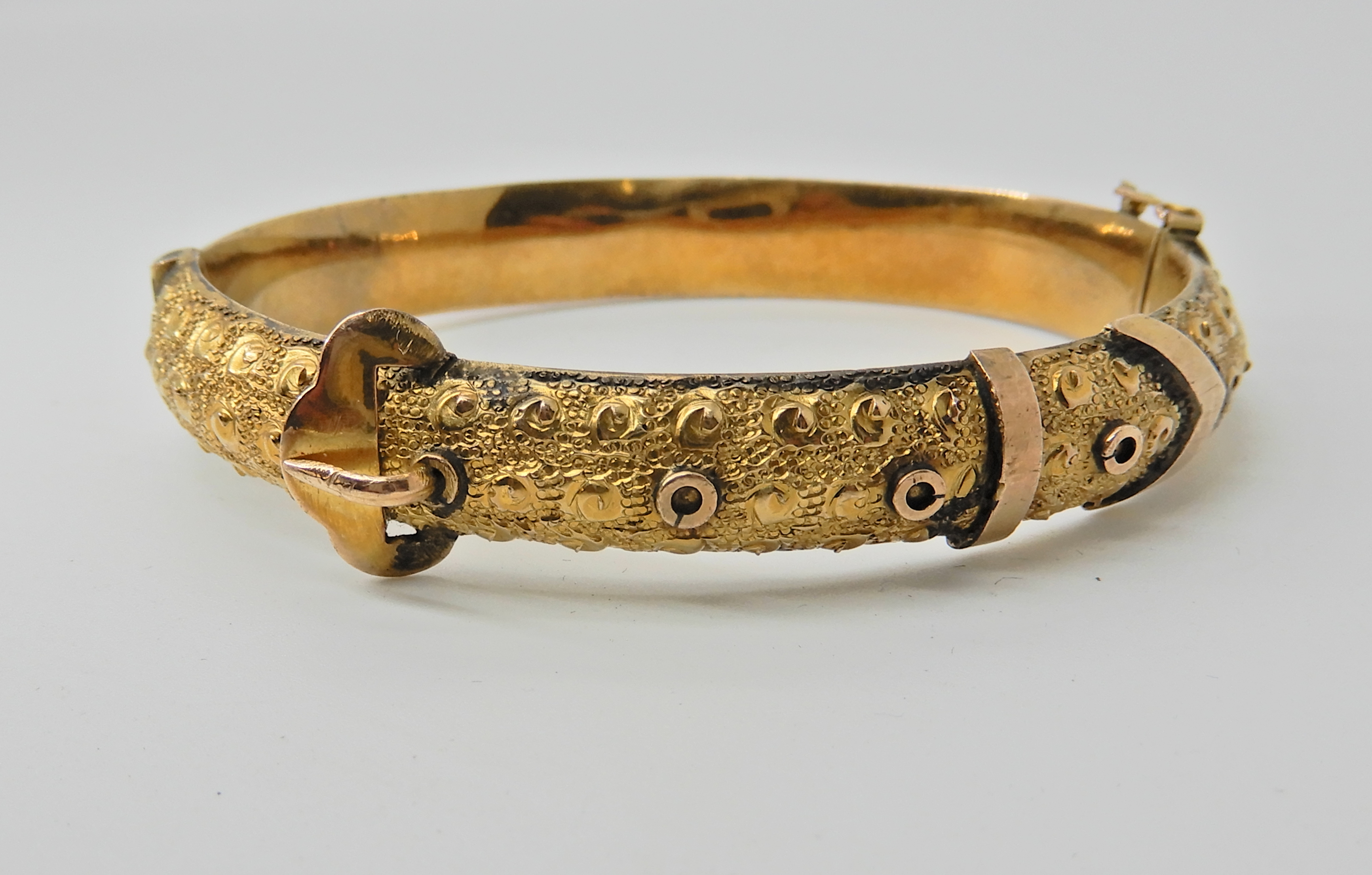 A 9ct gold bangle by Smith & Pepper, dated Birmingham 1918. In the ...