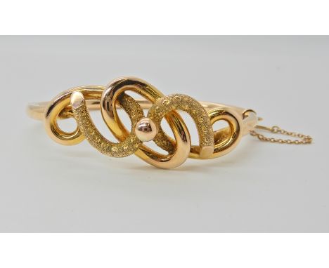 A 9ct gold knot detailed bangle, inner dimensions 6.2cm x 4.5cm, weight 10.1gms