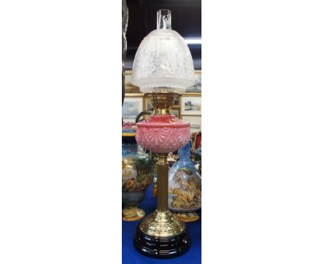 A milk cranberry glass and brass oil lamp with reeded column and etched shade, 70cm including funnel
