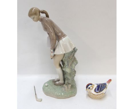 A Lladro figure of a girl playing golf and a Royal Crown Derby bird paperweight (2)