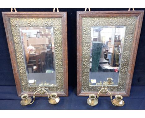 A PAIR OF EDWARDIAN OAK FRAMED GIRANDOLES with embossed brass inner slips, bevelled mirror plates, and twin brass sconces, ea