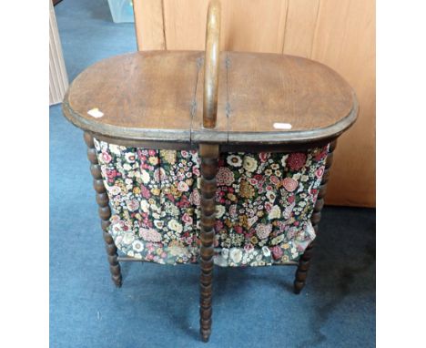 A 1920S OAK -FRAMED OVAL SEWING BASKET with twin hinged top, on bobbin-turned legs (later bag)