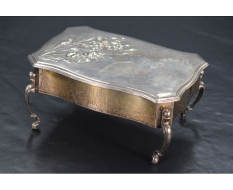 An Edwardian silver jewellery box, in the form of a commode table with serpentine outline and canted corners, the hinged cove