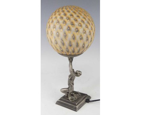 An Art Deco style patinated and cast metal figural table lamp, having a bright coloured mottled domed shade, supported on a f