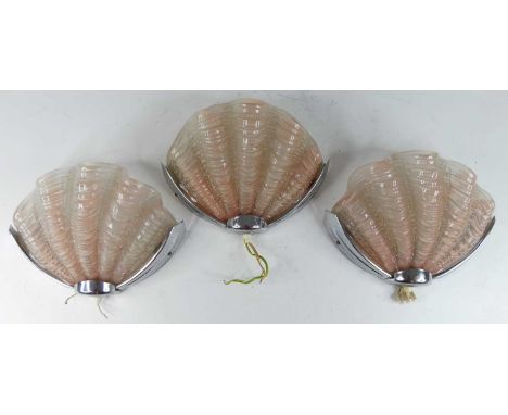 A set of three Art Deco chromed metal and moulded peach glass inset fan wall lights, each with on/off button to lower centre,