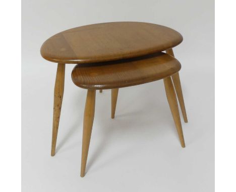 A 1960s Ercol blond elm 'Pebble' nest of two occasional tables, raised on plain turned tapering supports, the largest h.36cm,