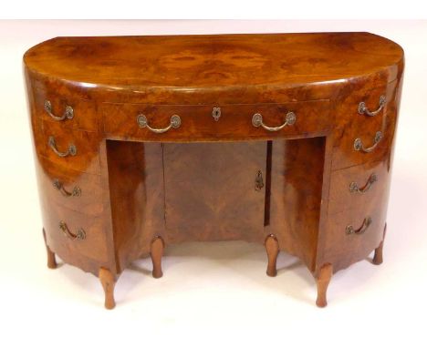 An Art Deco figured walnut kneehole desk by Maurice Adams Ltd, of kidney form with central frieze drawer, flanked by four sho