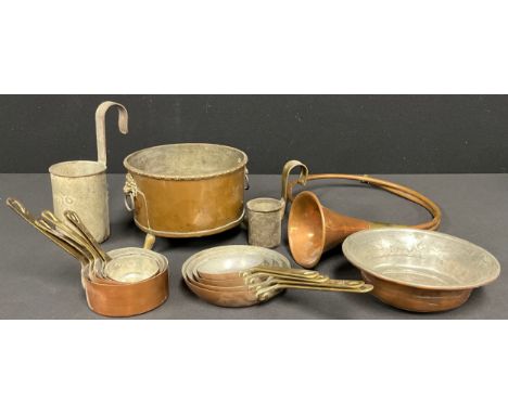 A set of five graduated copper small pans; a similar set of four copper saucer pans; a copper bugle; a pint measure; a copper