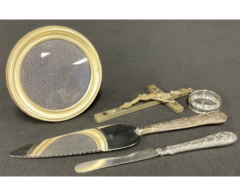A silver circular easel photograph frame; a Victorian silver knife, a silver hafted cake slice; a silver napkin ring; a Frenc