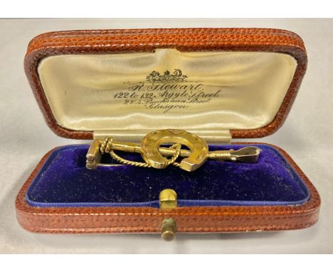 An early 20th century 9ct gold bar brooch, cast as a horseshoe and riding crop, 4.5cm wide, cased, 2.9g