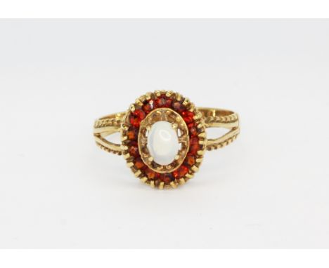 A hallmarked 9ct yellow gold ring set with an oval cabochon cut opal surrounded by garnets, (R.5).