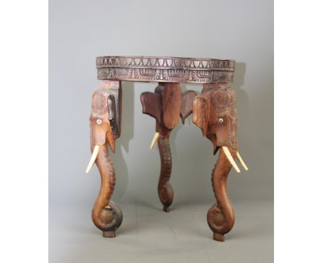 A small Indian carved hardwood table with elephants trunk legs, Dia. 30cm. H. 38cm.