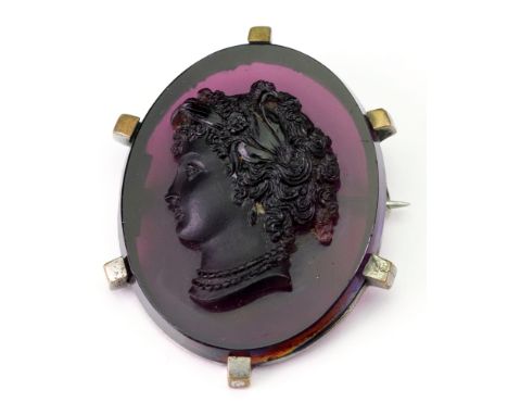 A Victorian amethyst coloured glass portrait brooch, modelled in high relief with a bust of a lady in profile, her hair raise