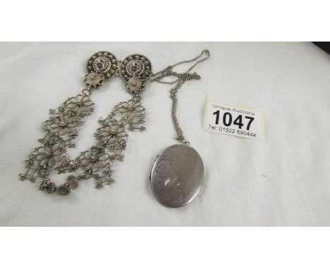 A silver cloak pin and a silver locket on chain.