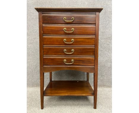 An Edwardian mahogany music cabinet with a moulded cornice above five drawers with fold down fronts, with a shelf below on sq