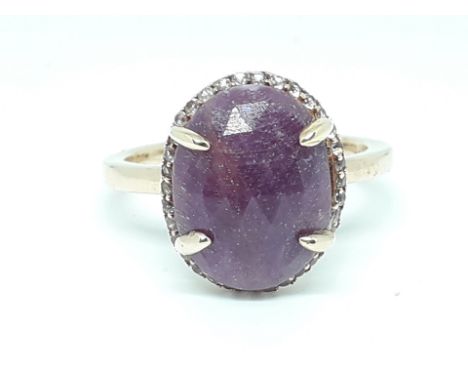 A silver gilt ring set with a central oval rose cut purple stone surrounded by colourless stones, marked '925', size V, with 
