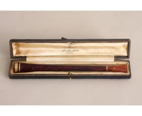 An early 20th century Alfred Dunhill cigarette holder, trumpet form, with amber mouth piece and 14ct gold tip, in its tooled 