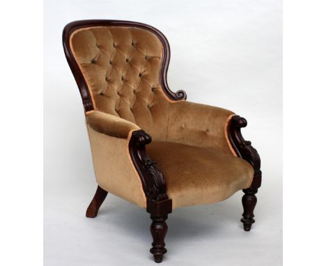 A Victorian walnut and mahogany button back armchair raised on fluted tapering feet