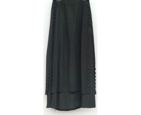 An Edwardian black silk layered skirt with covered button details to sides of garment.  There is some minor damage to waistba