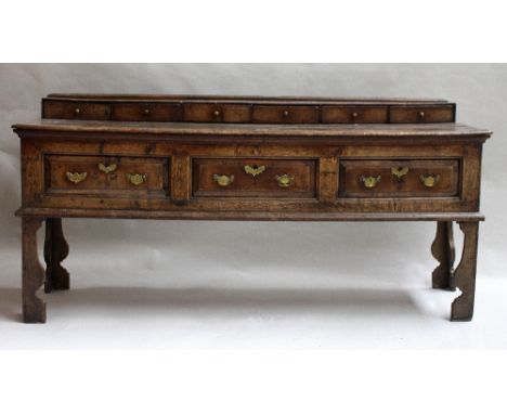 A late 17th century oak dresser base, six raised small drawers over rectangular top, above three drawers, on carved bracket f