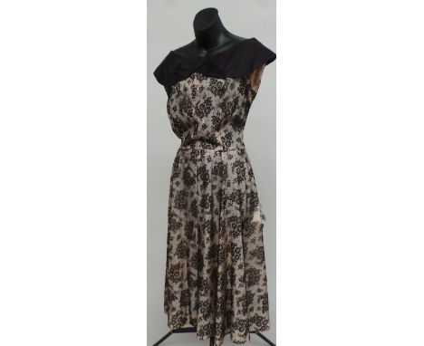 A 1950's black lace over cream cocktail dress with shawl collar and side zip. The lace has deteriorated in several places. Si