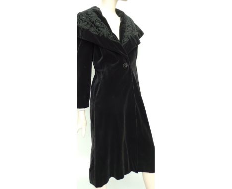 A beautifully tailored 1950's Edwardian style black velvet coat. This garment has a wide shawl collar embellished with cord e