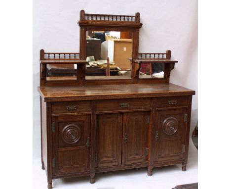 A Victorian oak sideboard, in the Aesthetic taste, triple mirrored top with spindle gallery, over three drawers, over three c