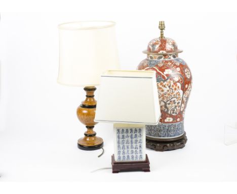A pair of contemporary Chinese lamps, with white rectangular ceramic bodies painted with blue symbols, placed upon wooden sta