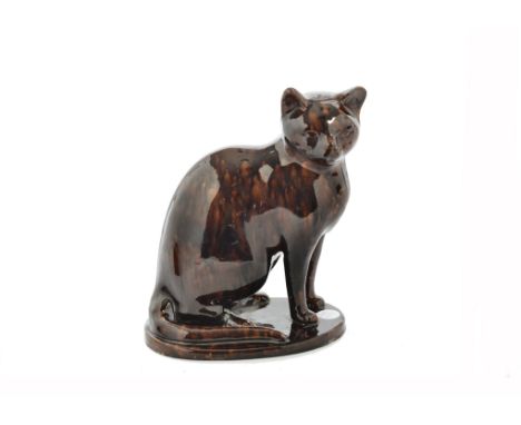 A 19th Century Canney Hill pottery treacle glaze model of a cat, Bishop Auckland c.1870, seated on its haunches upon an oval 