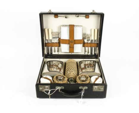 A picnic hamper for four, with a fitted interior, comprising cutlery, plates, cups, food containers, a flask and jars, within